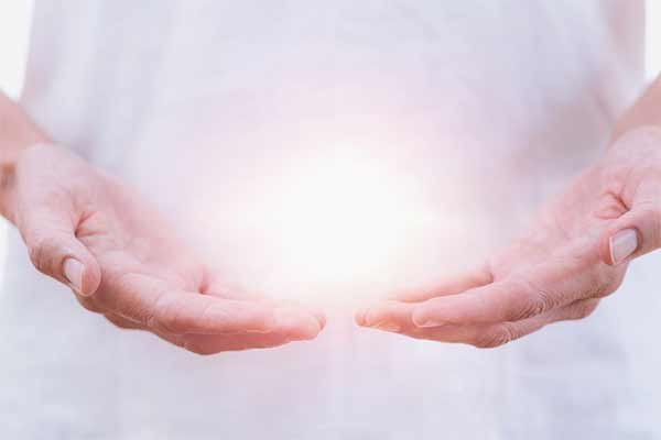 A glowing ball of light being held in a person's hands to represent tho hope provided by therapy treatments